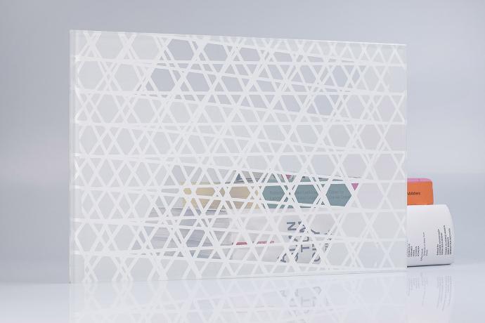A square piece of glass with a white pattern and books on a neutral background
