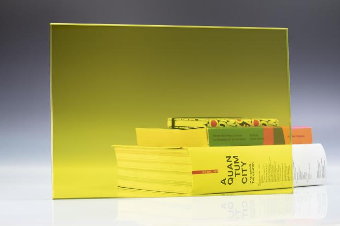 Četverokutni komad žutog transparentnog stakla i knjige na neutralnoj pozadini