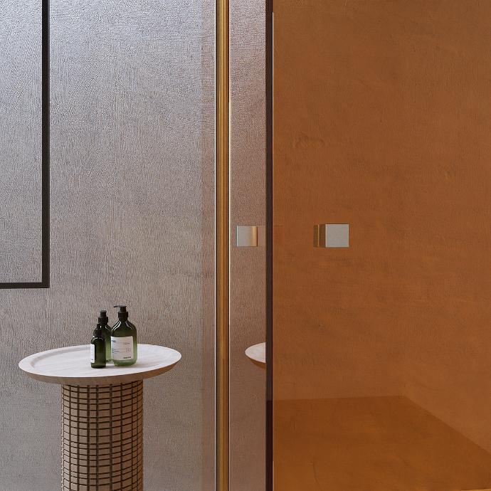 Detail of the glass doors of the shower cabin with a stool and cosmetics.