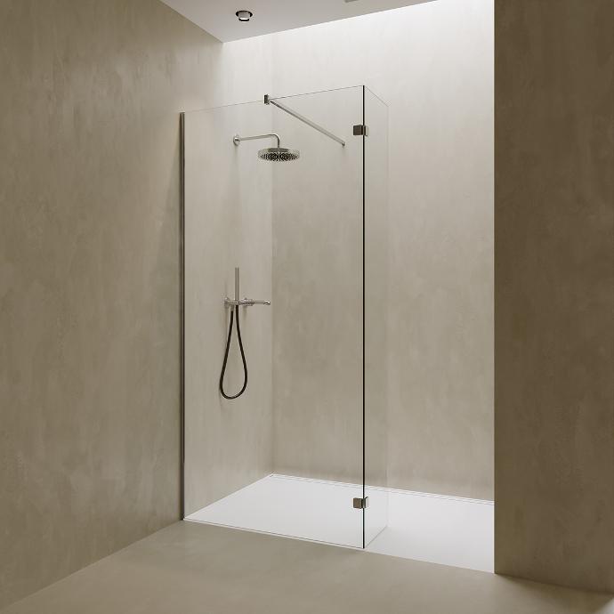 Walk-in shower in a niche with a fixed glass panel and splash protection.