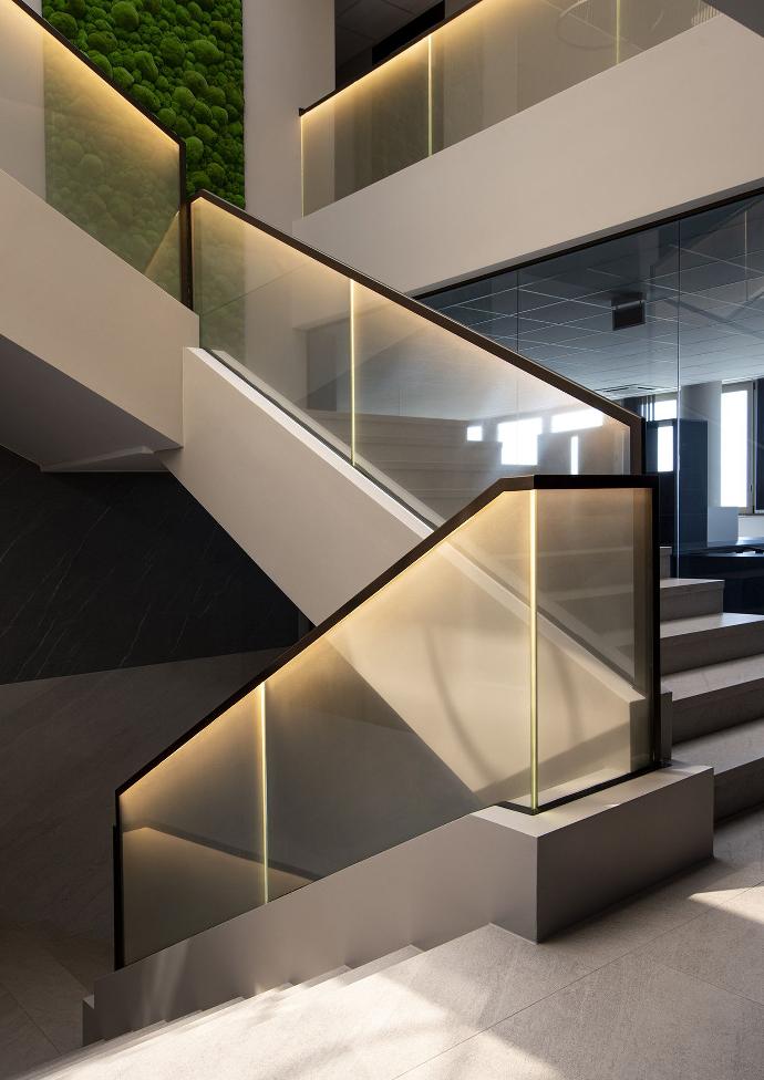 Illuminated glass staircase railing in a commercial building.