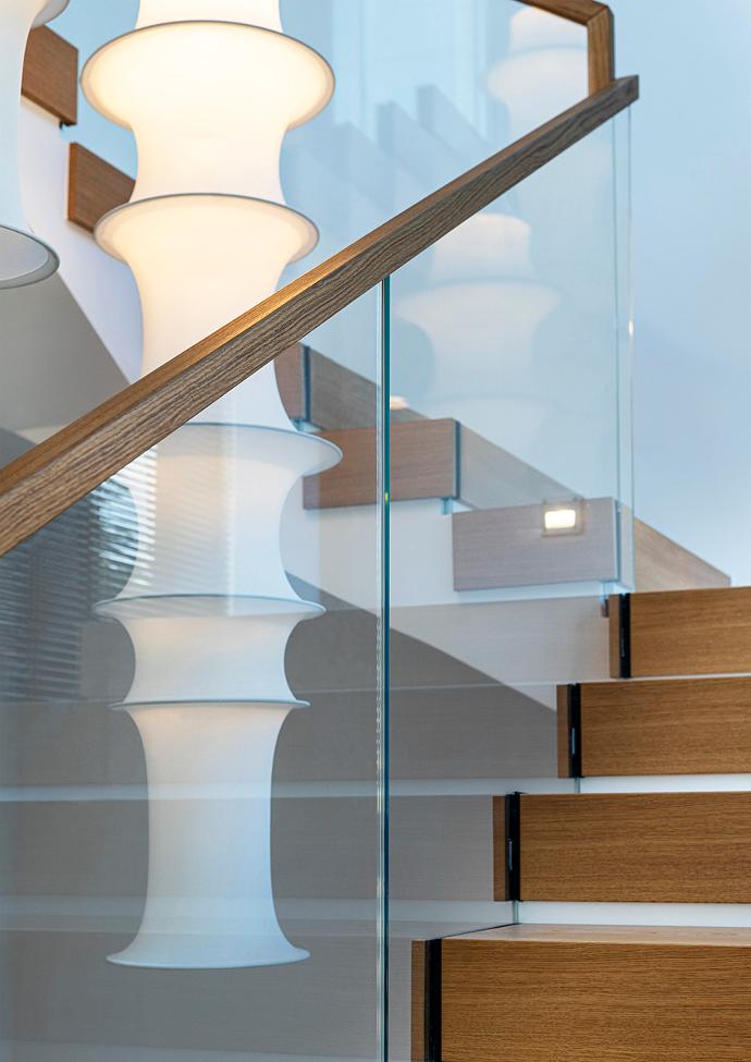 Glass railing of an interior staircase with a wooden handrail.