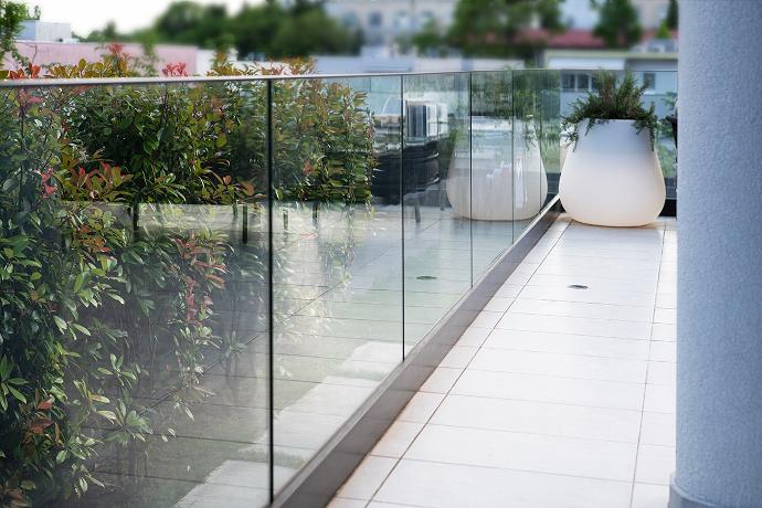 Glass railing on a terrace with greenery.