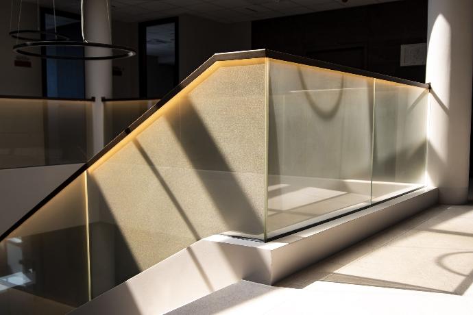 Illuminated glass staircase railing in a commercial building.