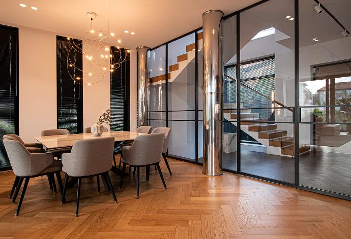 Modern dining room with a glass partition wall and stainless steel columns.