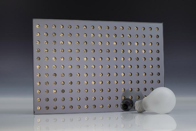 A square piece of gray mirror with a dot pattern and a light bulb on a neutral background